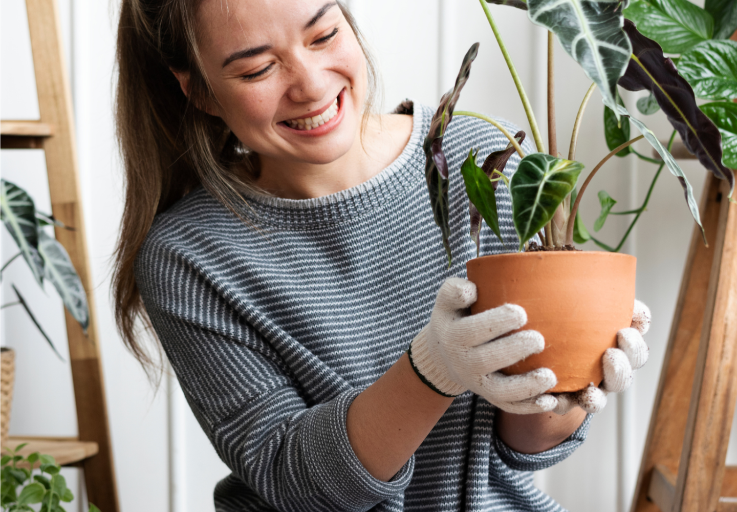 Mulher segurando vaso de planta e sorrindo